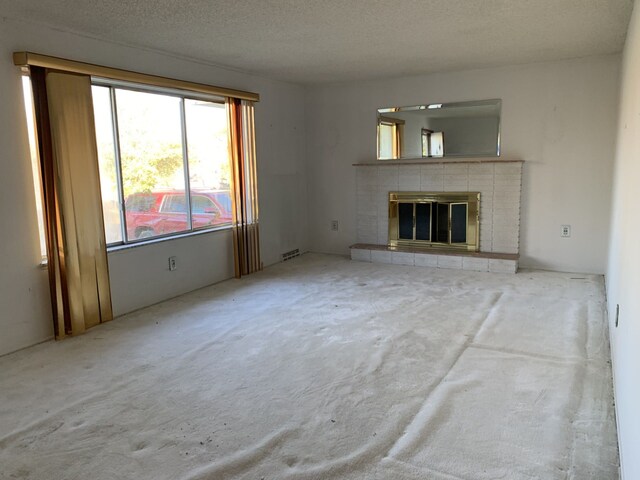 unfurnished living room featuring a tile fireplace and a textured ceiling