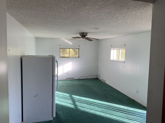 unfurnished bedroom with carpet flooring, ceiling fan, a textured ceiling, and white refrigerator