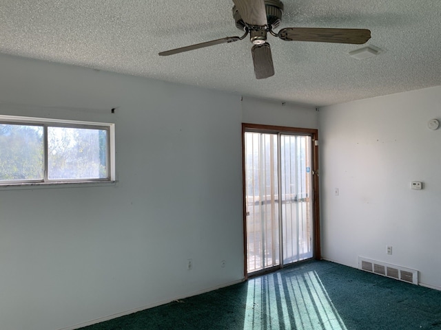 spare room featuring ceiling fan, a textured ceiling, and dark colored carpet