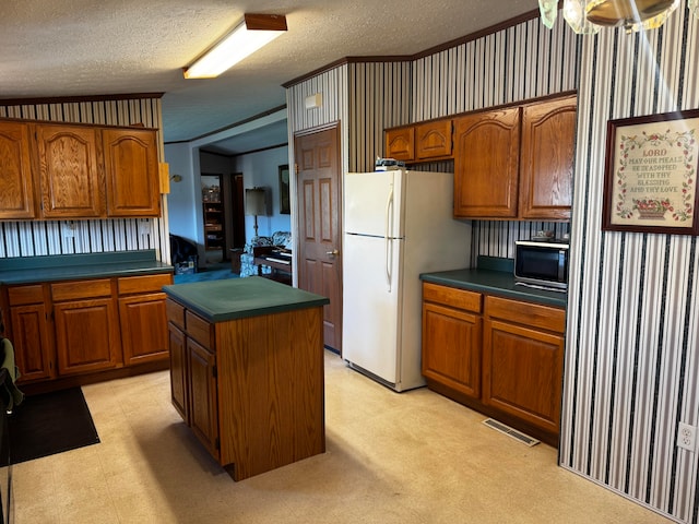 kitchen with a center island, light colored carpet, white refrigerator, and a textured ceiling