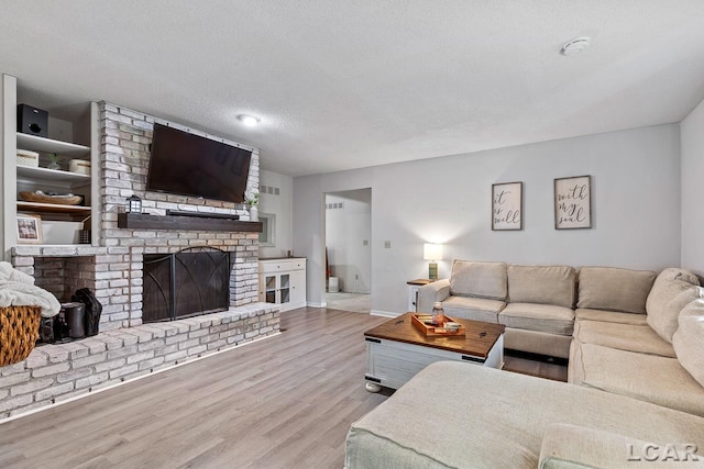 living room featuring a textured ceiling, a fireplace, and light hardwood / wood-style flooring