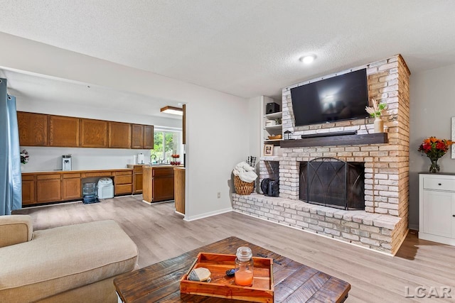 living room featuring a textured ceiling, light wood-type flooring, and a brick fireplace