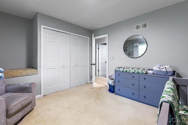 bedroom featuring light colored carpet, a textured ceiling, and a closet