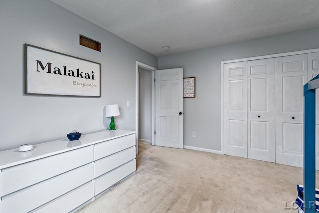 bedroom featuring light carpet, a textured ceiling, and a closet