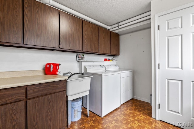 clothes washing area with cabinets, a textured ceiling, separate washer and dryer, and parquet floors