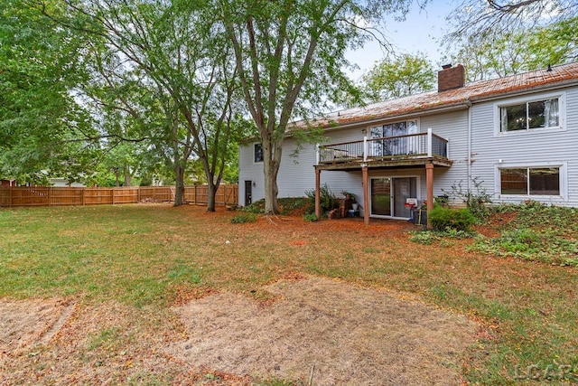 back of house featuring a lawn and a wooden deck