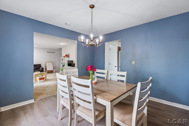 dining space with hardwood / wood-style floors and a notable chandelier