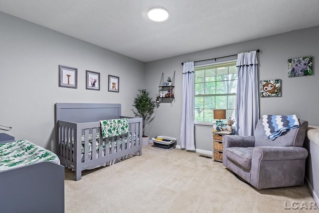 carpeted bedroom with a textured ceiling and a nursery area