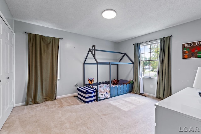 carpeted bedroom with a textured ceiling and a closet