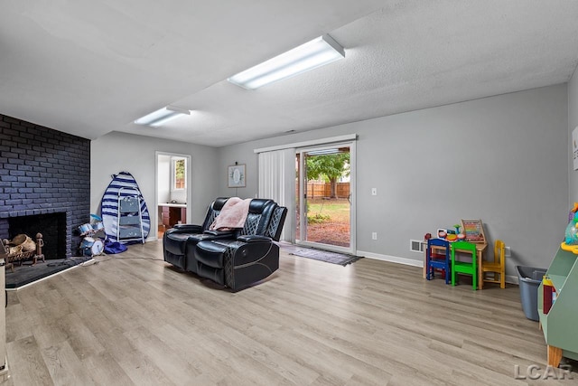 sitting room with a fireplace, a textured ceiling, and light wood-type flooring