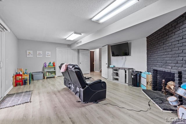 interior space featuring a brick fireplace, a textured ceiling, and light wood-type flooring