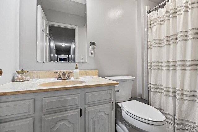 bathroom featuring a shower with curtain, vanity, and toilet