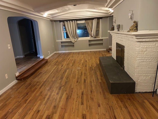 unfurnished living room with hardwood / wood-style floors and a stone fireplace