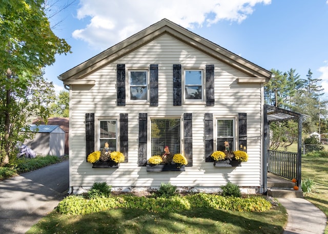 view of front of property featuring a front lawn and a storage unit