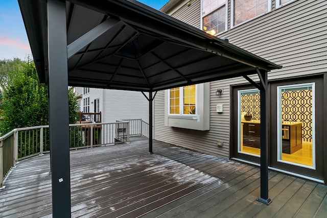 deck at dusk featuring a gazebo