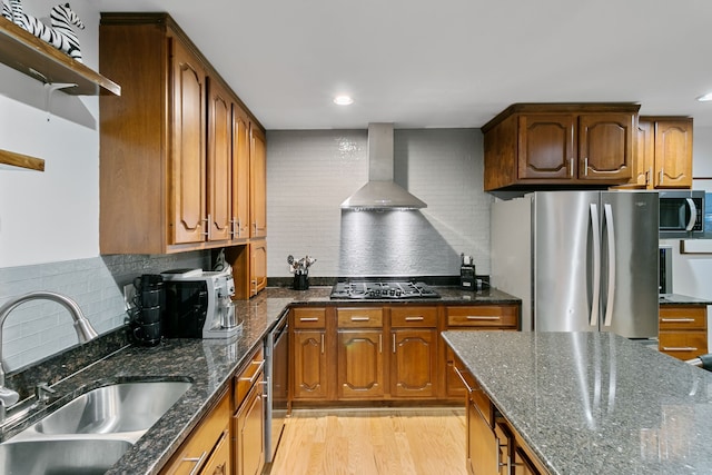 kitchen with decorative backsplash, stainless steel appliances, wall chimney exhaust hood, and sink