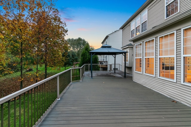 deck at dusk featuring a gazebo