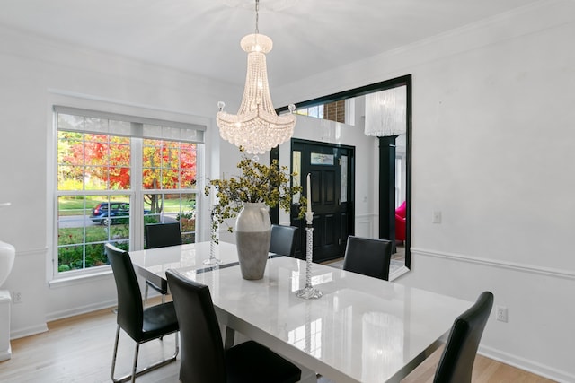 dining room featuring light wood-type flooring, ornamental molding, and a chandelier