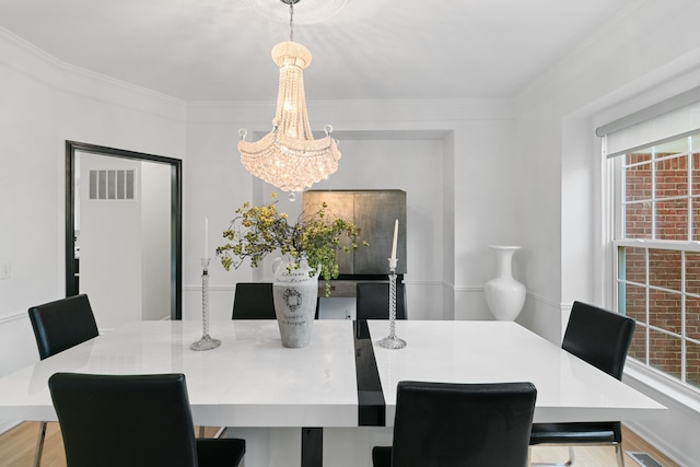 dining room featuring light hardwood / wood-style floors, ornamental molding, and a notable chandelier