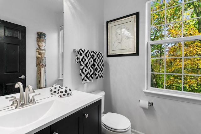 bathroom featuring vanity, a healthy amount of sunlight, and toilet