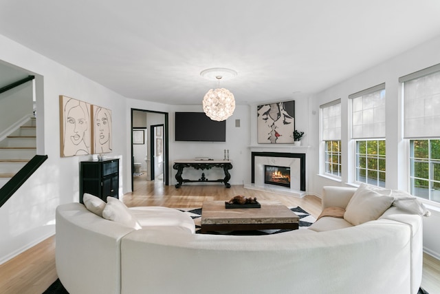 living room featuring a notable chandelier, a fireplace, and light hardwood / wood-style flooring