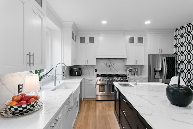 kitchen featuring light stone countertops, white cabinets, custom exhaust hood, and appliances with stainless steel finishes