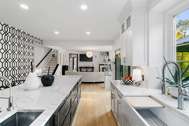 kitchen with light stone countertops, tasteful backsplash, sink, light hardwood / wood-style flooring, and white cabinetry