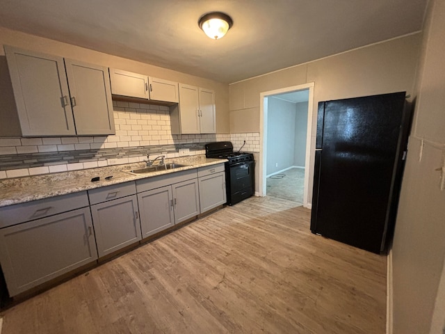 kitchen featuring gray cabinetry, sink, tasteful backsplash, black appliances, and light wood-type flooring