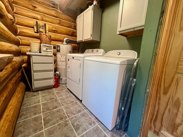 clothes washing area with log walls, washer and clothes dryer, cabinets, and water heater