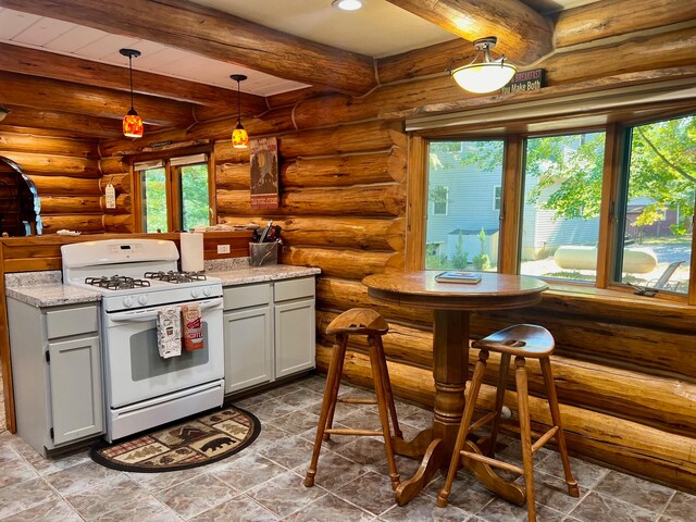 kitchen featuring light stone countertops, log walls, beam ceiling, decorative light fixtures, and white range with gas stovetop