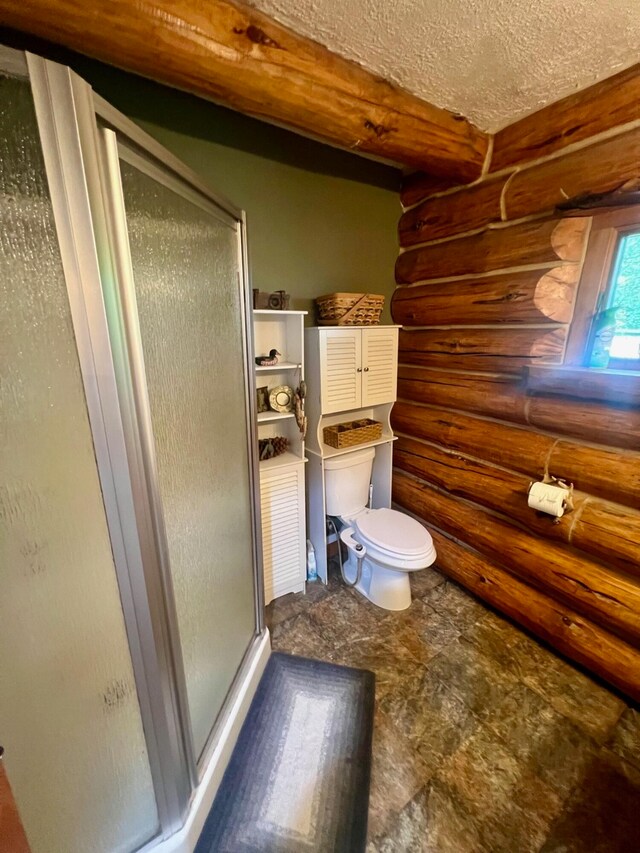 bathroom featuring log walls, a textured ceiling, toilet, and a shower with door