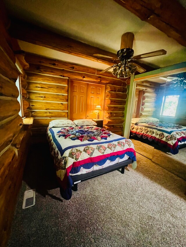 bedroom featuring carpet flooring, ceiling fan, beamed ceiling, and log walls