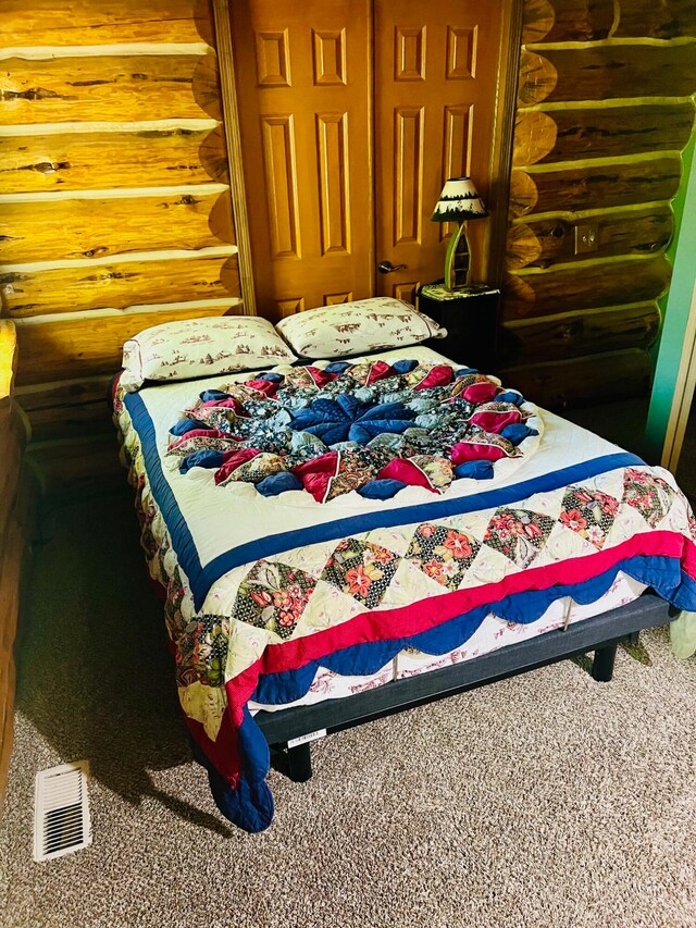 bedroom with carpet and log walls