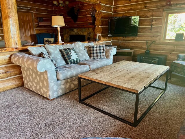 carpeted living room with a stone fireplace and log walls