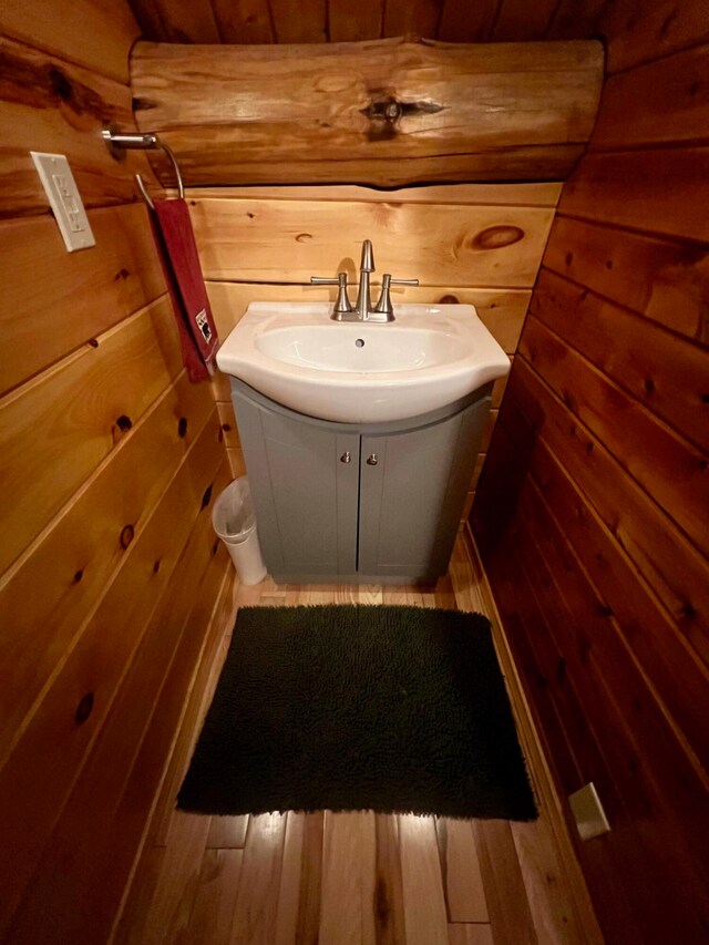 bathroom featuring hardwood / wood-style floors, vanity, and wood walls