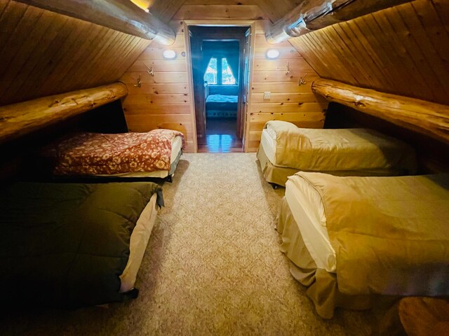 carpeted bedroom with wood walls, wood ceiling, and vaulted ceiling