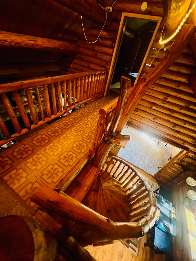 stairway featuring log walls and hardwood / wood-style floors