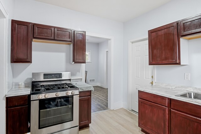 5015 Vancouver St, Detroit, MI 48204 - kitchen with stainless steel range with gas cooktop, light wood-type flooring, light countertops, reddish brown cabinets, and baseboards