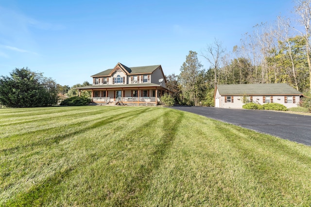 view of front of house featuring a porch, an outbuilding, and a front lawn