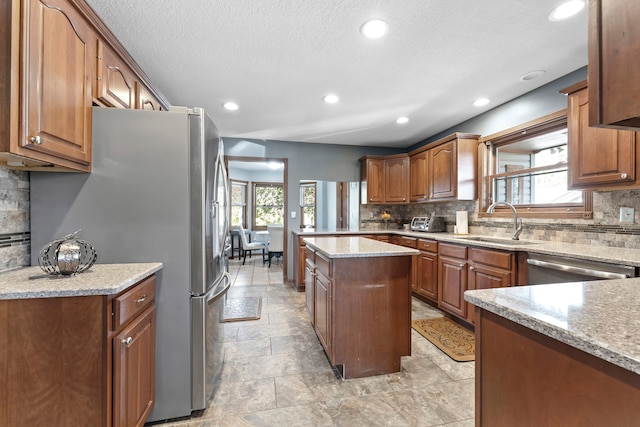 kitchen featuring light stone countertops, sink, a kitchen island, and appliances with stainless steel finishes