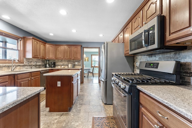 kitchen with decorative backsplash, sink, light stone counters, and appliances with stainless steel finishes