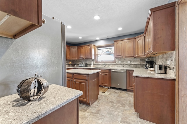 kitchen featuring light stone countertops, sink, stainless steel dishwasher, backsplash, and a kitchen island