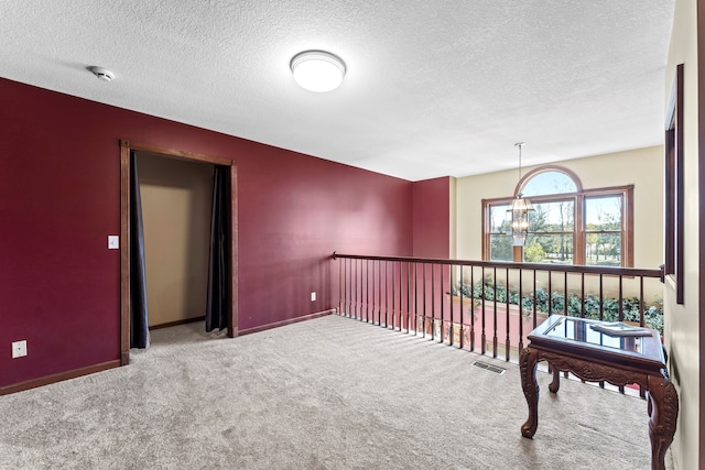 interior space with carpet flooring, a textured ceiling, and an inviting chandelier