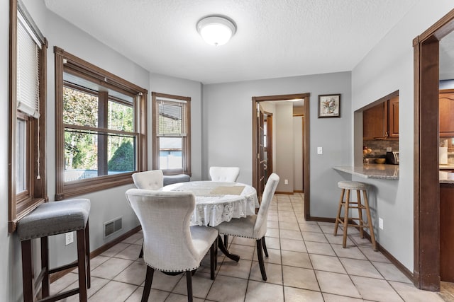 dining area with light tile patterned floors and a textured ceiling