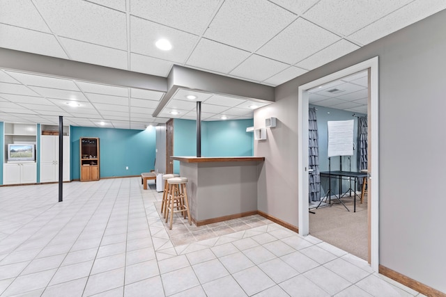 bar with a paneled ceiling and light tile patterned floors