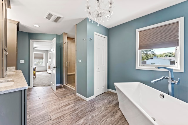 bathroom with separate shower and tub, vanity, and a notable chandelier