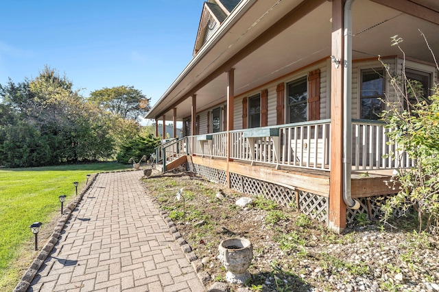 view of side of home featuring covered porch and a yard