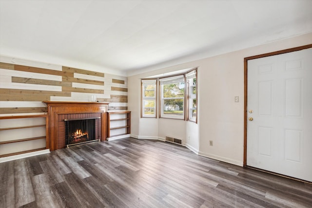 unfurnished living room with dark hardwood / wood-style flooring and a brick fireplace