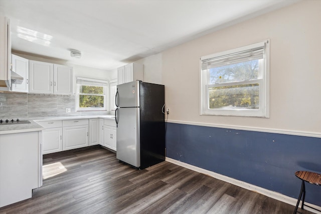 kitchen with white cabinetry, dark hardwood / wood-style flooring, backsplash, stainless steel fridge, and black cooktop