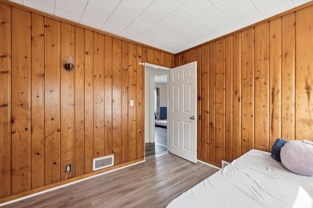 bedroom with light hardwood / wood-style floors and wooden walls